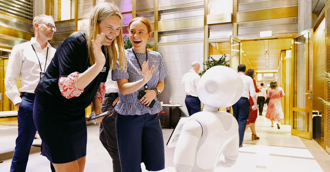 Norges Bank Investment Management employees interacting with a humanoid robot during a tech event.