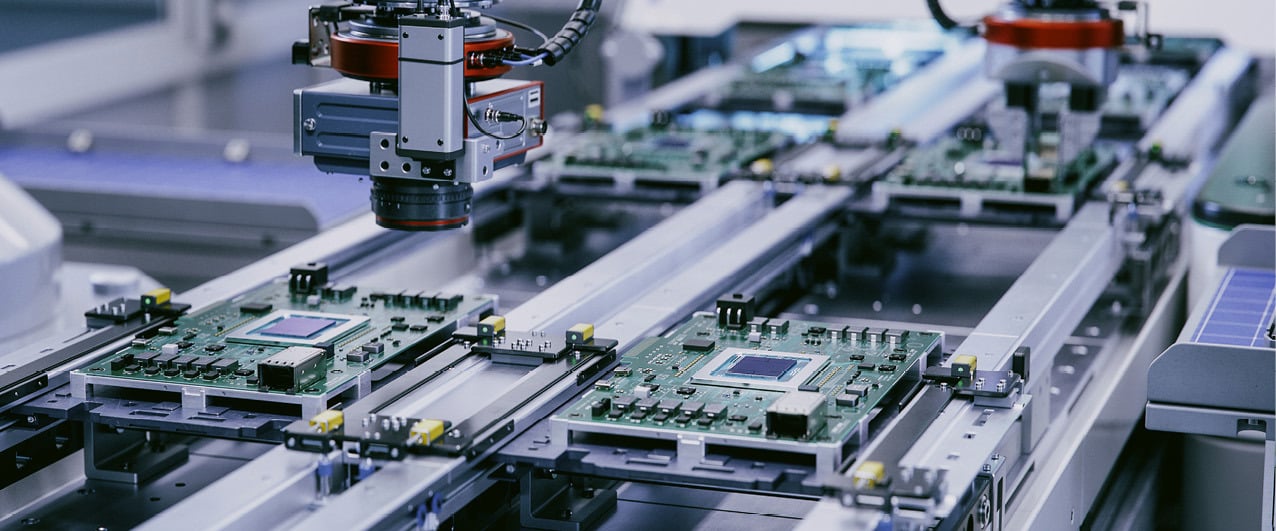 Robotic arms assembling circuit boards on a production line.