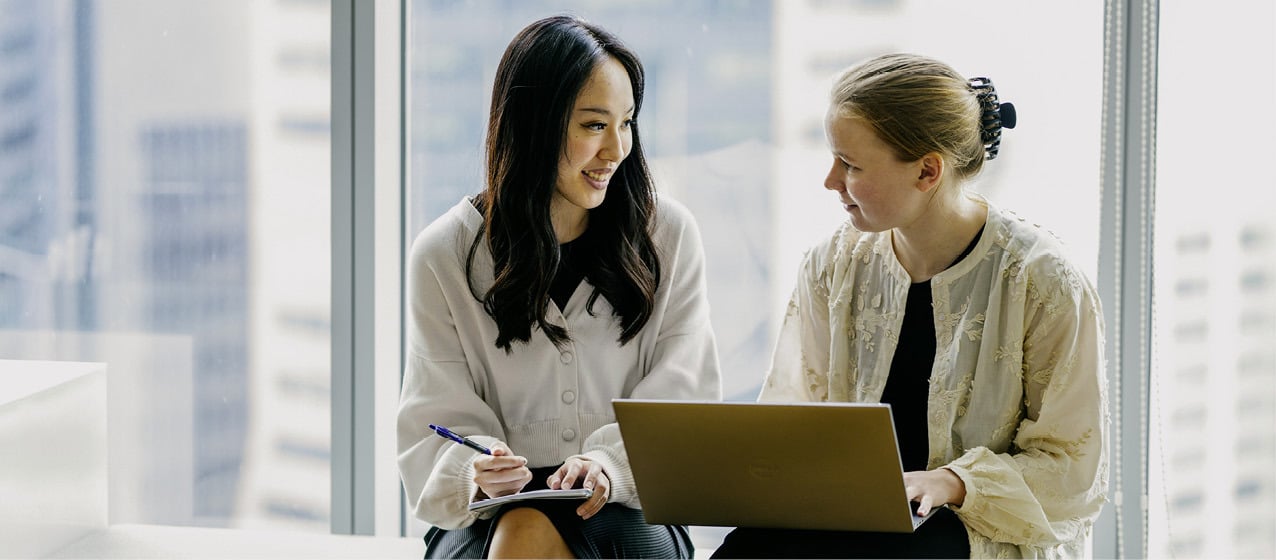 Two Norges Bank Investment Management employees collaborating in the Singapore office, with a cityscape visible through the window.