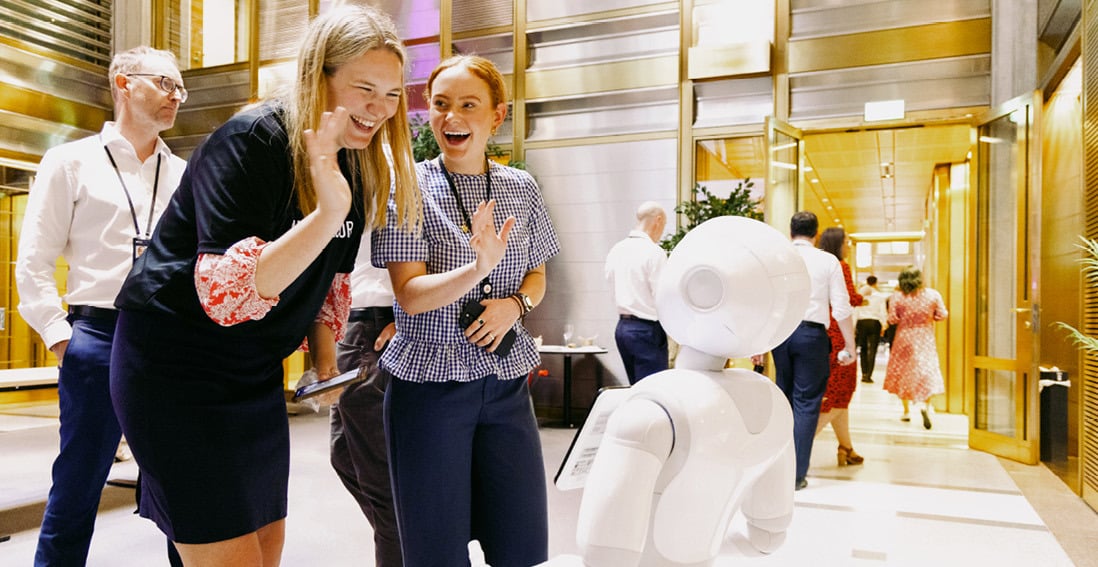 To ansatte i Norges Bank Investment Management interagerer med en humanoid robot under et teknologiarrangement.