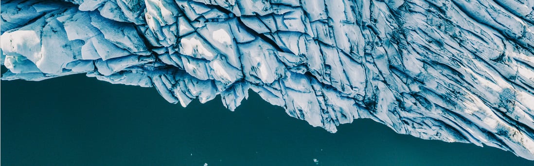 Aerial photo of glacier against dark ocean.