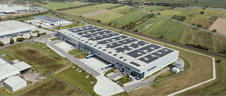 Aerial view of a logistics property with solar panels on the roof in a rural area.