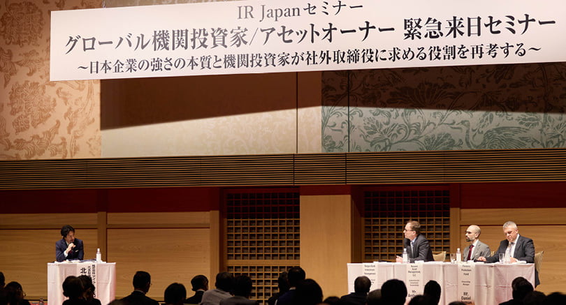 Three people on stage at an IR Japan seminar in Tokyo.